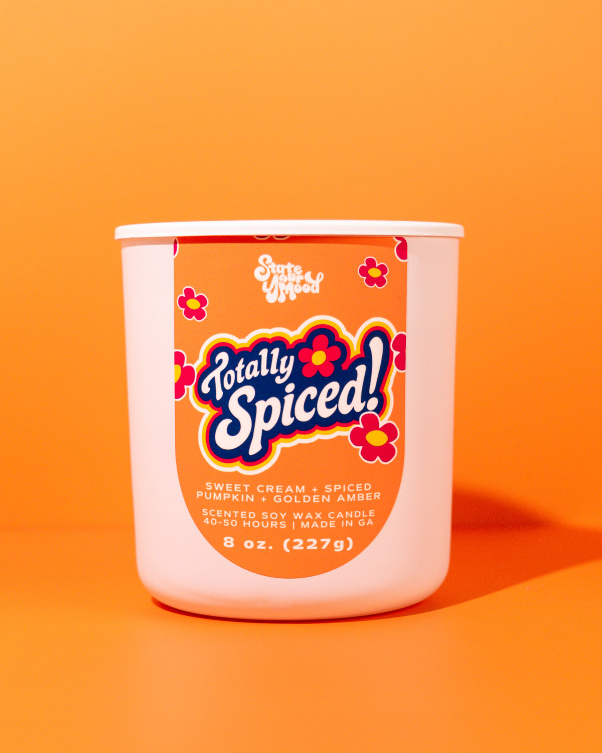 A 8 oz scented soy wax candle in a white plastic tub with a retro orange label reading 'Totally Spiced!' by Santa Maria, set against a solid orange background.