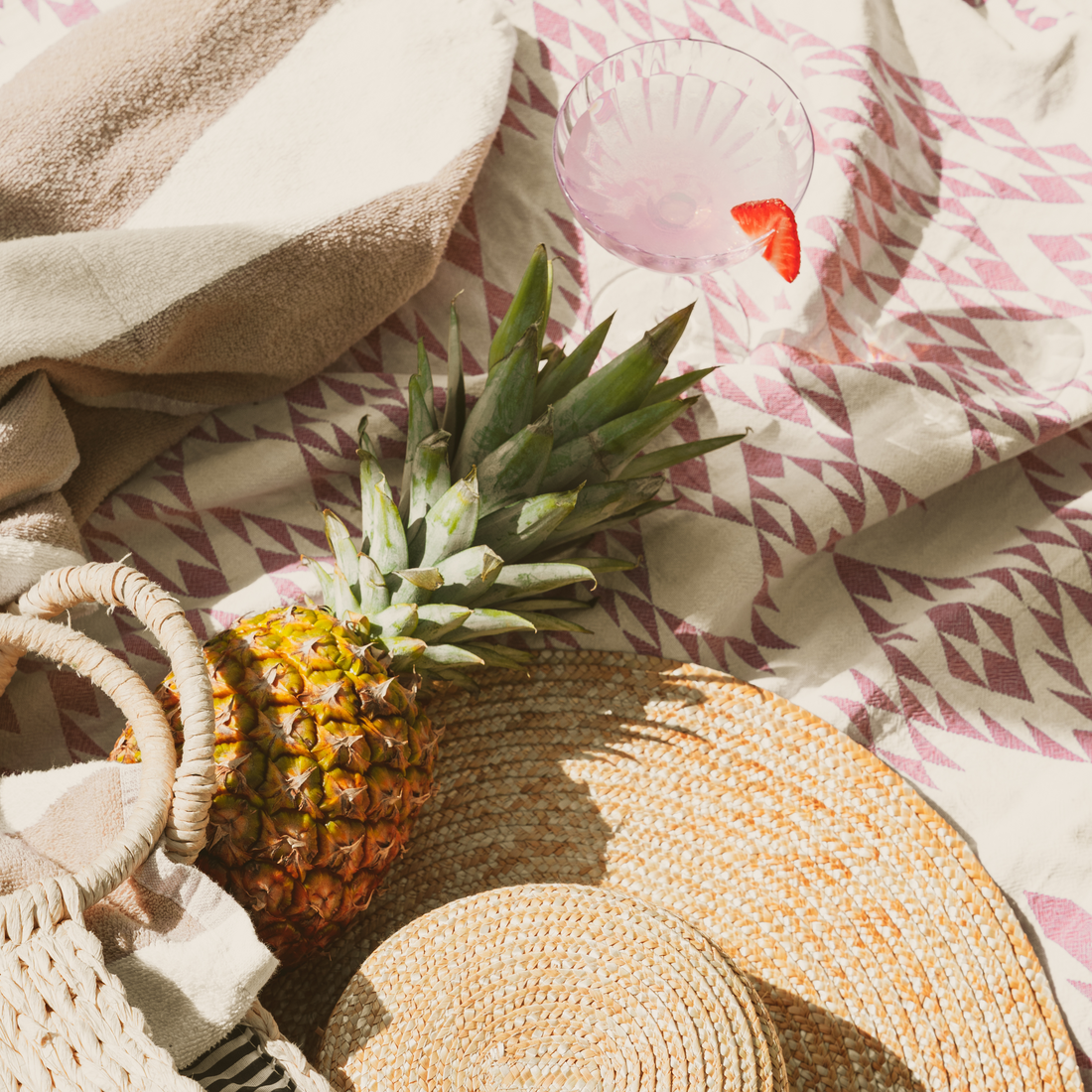 Modern poolside image with a pineapple, beach hat, and refreshing beverage.