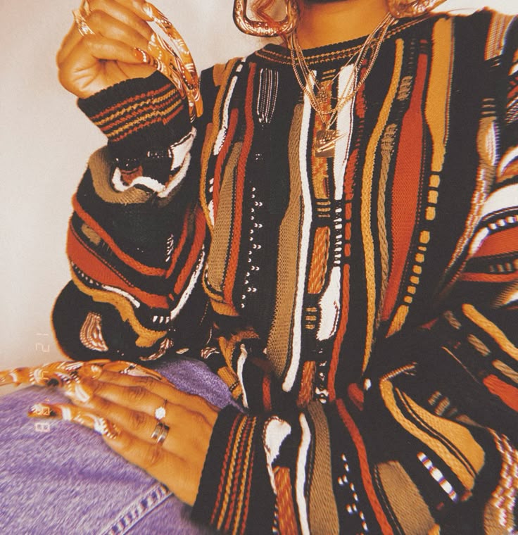 Person wearing a colorful patterned outfit with gold jewelry.